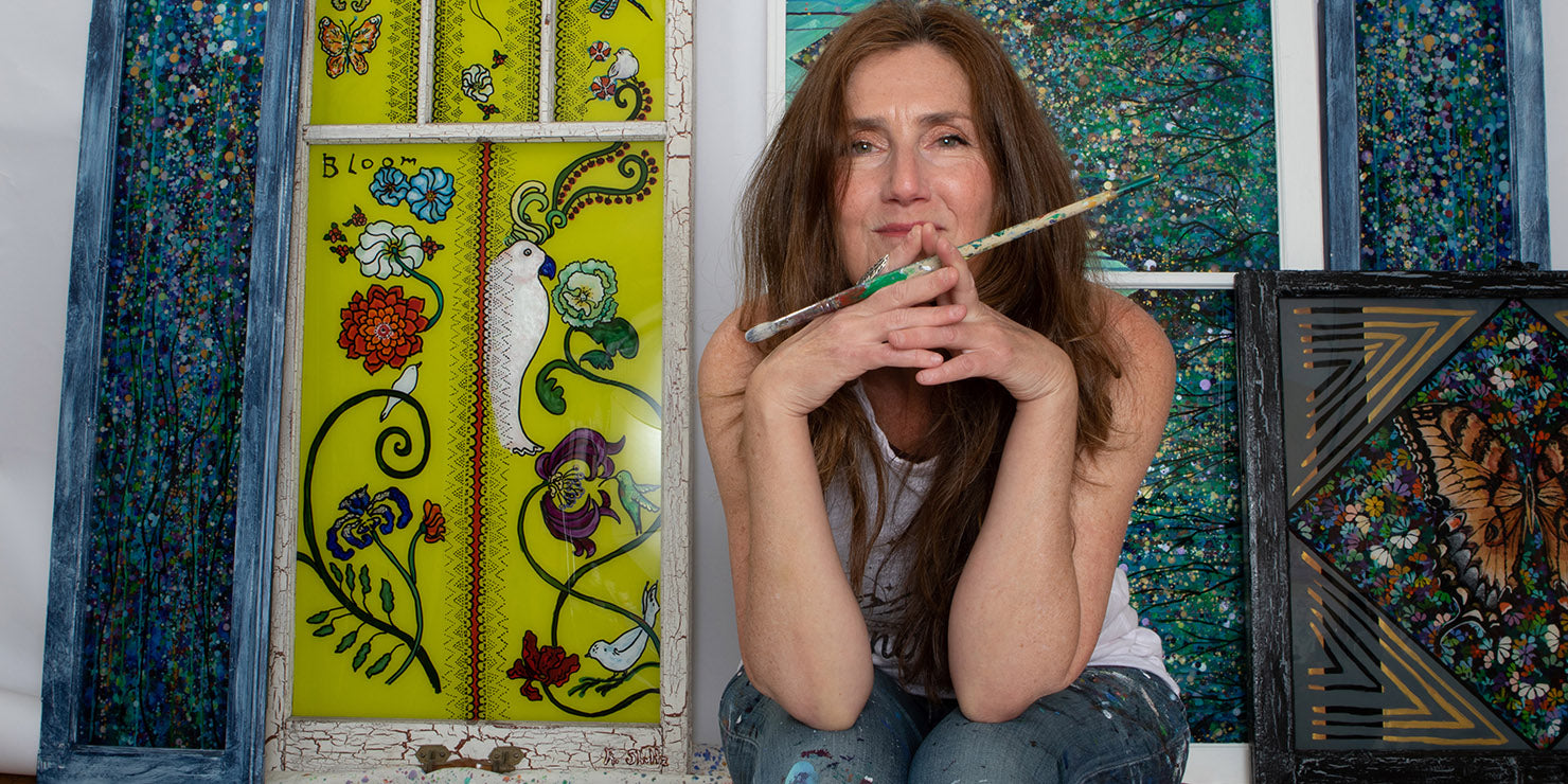 Rachel Shultz posing with a collection of Paintings in Windows