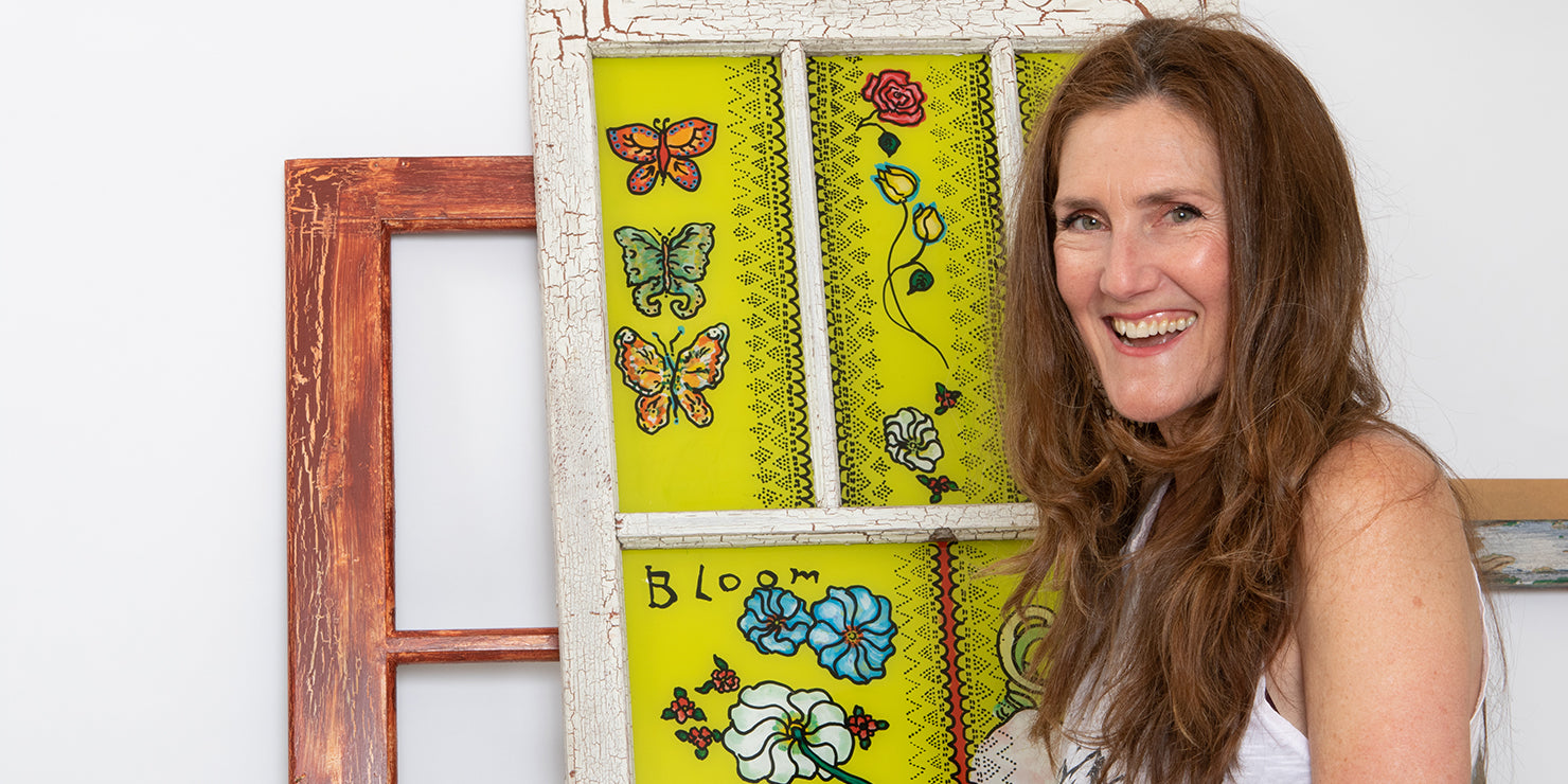 Rachel Shultz posing with a recently completed painting in window (Bloom)